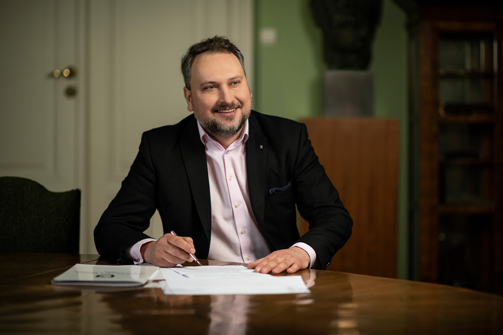Prorektor Bartłomiej Struzik podpisuje dokumenty przy biurku