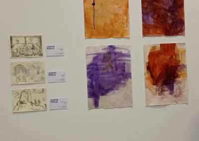 Zespół prac malarskich powieszonych na ścianie.